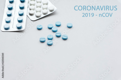 Blue and white medical pills on a white background with the word: coronavirus. 2019-nCov. Coronavirus epidemic concept