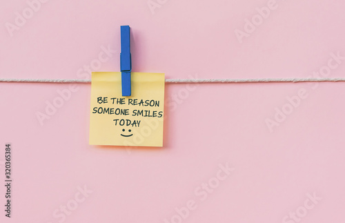 Motivational and inspirational quotes - Be the reason someone smiles today. Text on hanging paper note.