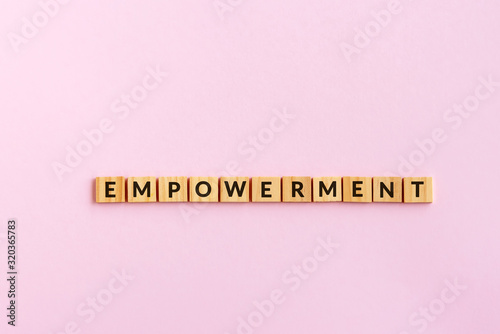 Empowerment text wood blocks. Pink background.