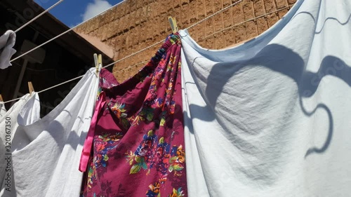 laundry washing line with plastic and wooden pegs holding clean washed clothing to air dry outside in courtyard on a sunny day photo