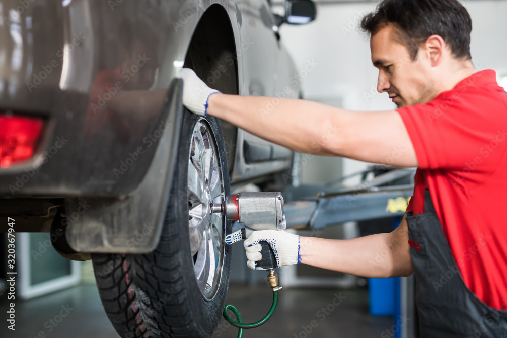 Auto mechanic in his workshop changing tires or rims at service