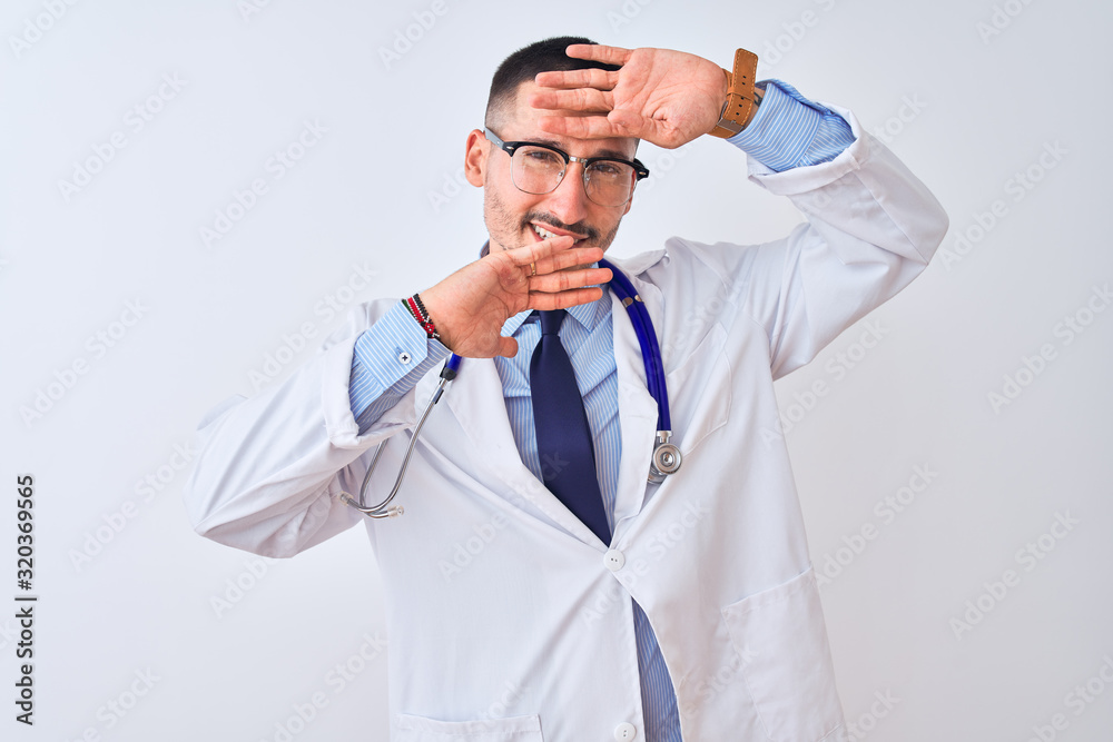 Young doctor man wearing stethoscope over isolated background Smiling cheerful playing peek a boo with hands showing face. Surprised and exited