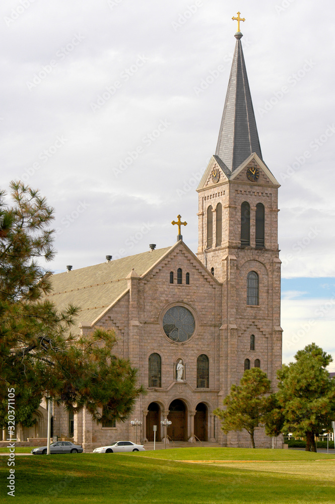 The front of a christian church with a steeple, cross, round stained glass window in downtown Denver, Colorado on an autumn's morning. 