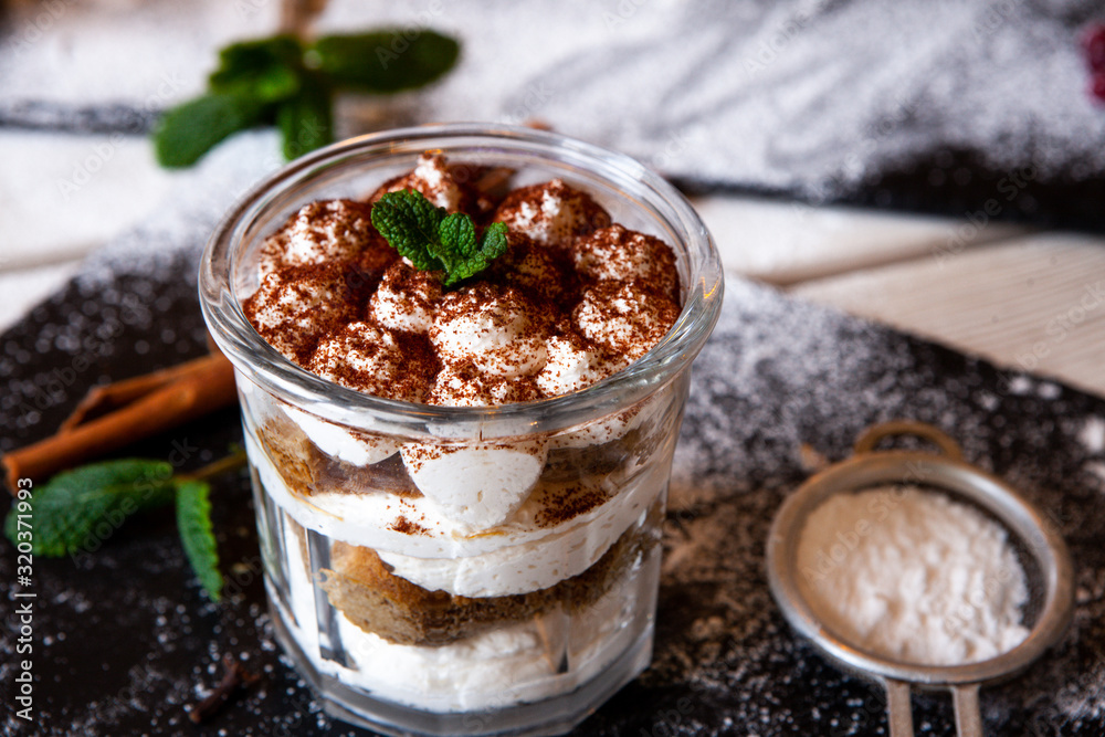 Tiramisu cake in glass, classic Italian dessert with mascarpone cream and cocoa. selective focus. Tiramisu cake in glass, classic Italian dessert with mascarpone cream and cocoa. selective focus.