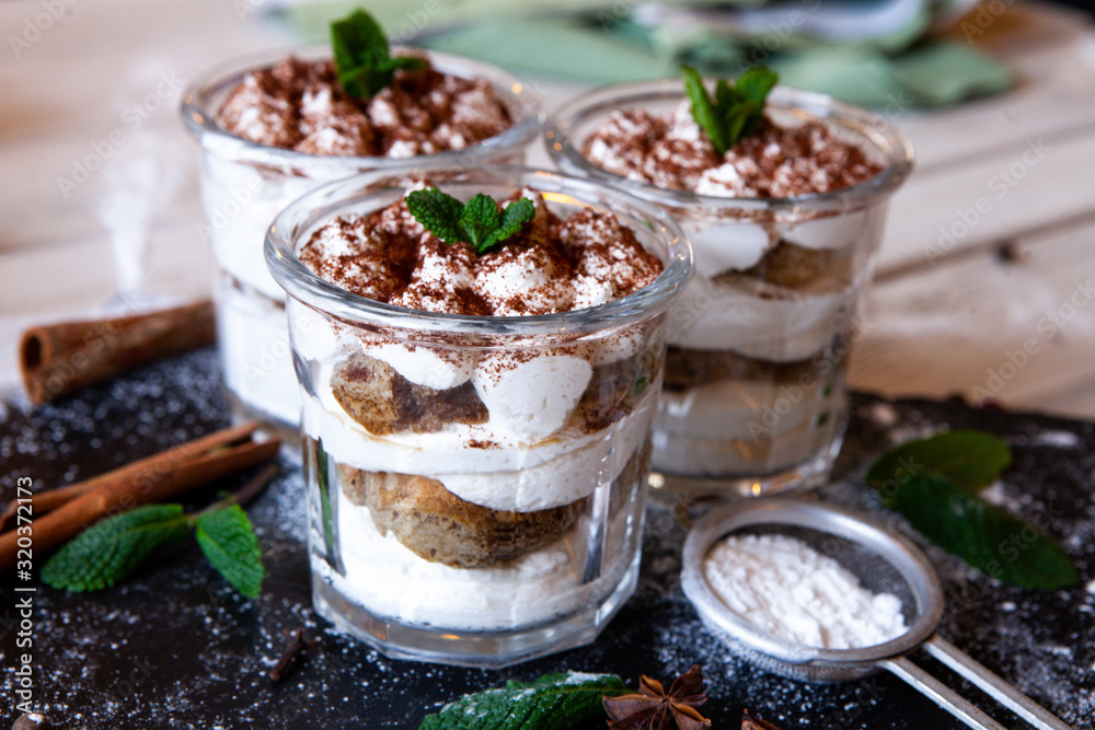 Tiramisu cake in glass, classic Italian dessert with mascarpone cream and cocoa. selective focus. Tiramisu cake in glass, classic Italian dessert with mascarpone cream and cocoa. selective focus.
