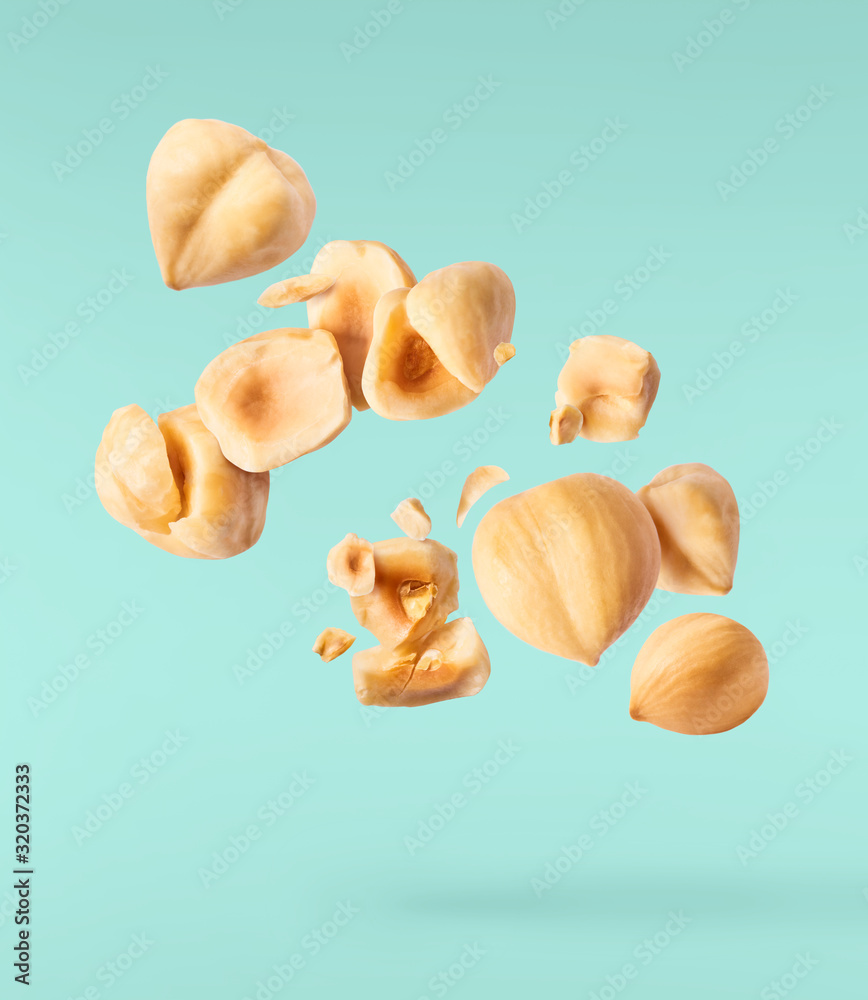 Fototapeta premium Hazelnuts crushed into pieces, frozen in the air.
