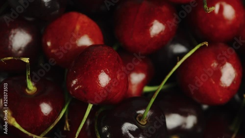 Close Up of bright red cherries in a bowl, firstly being picked up and then being dropped back in. photo