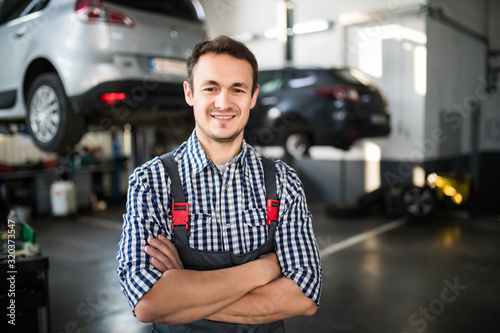 Portrait of a young beautiful car mechanic in a car workshop, in the background of service. Concept: repair of machines, fault diagnosis, repair specialist, technical maintenance and on-board computer
