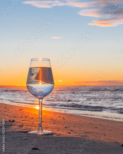 Reflet dans un verre au coucher du soleil sur une plage.