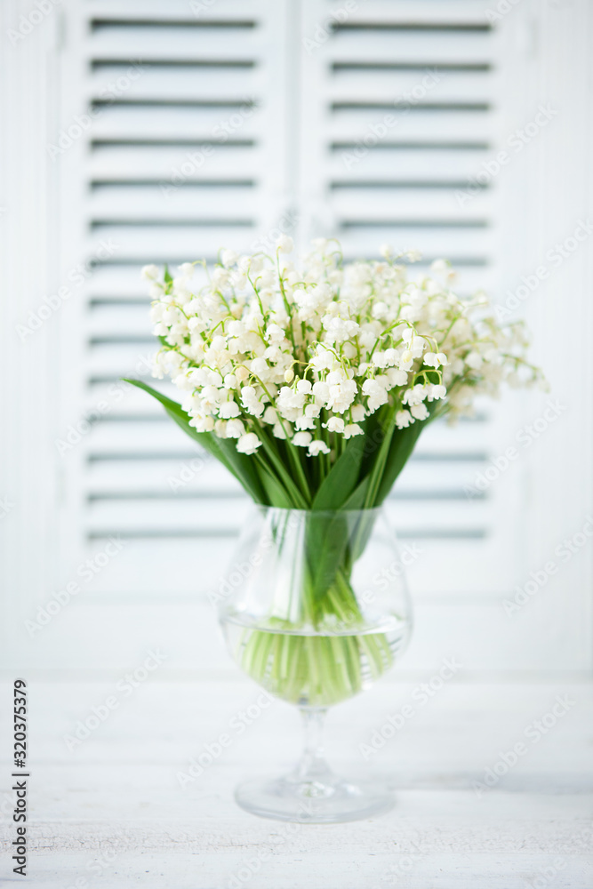 Bouquet of fresh white lilies of the valley in a glass goblet Bouquet of fresh white lilies of the valley in a glass goblet