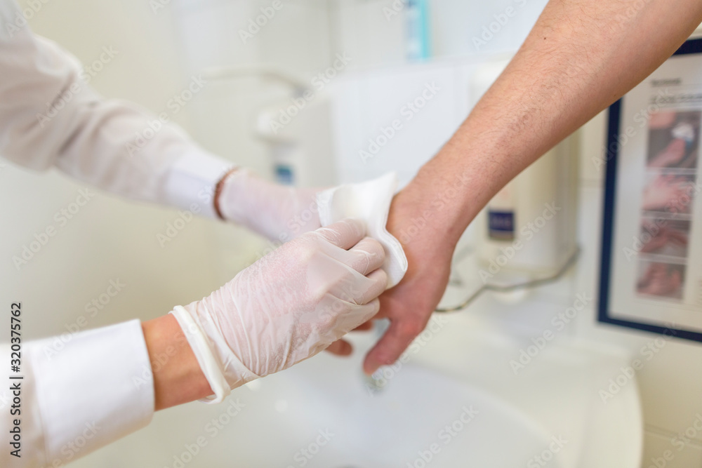 Nurse disinfects a patients hand at a sink Nurse disinfects a patients hand at a sink
