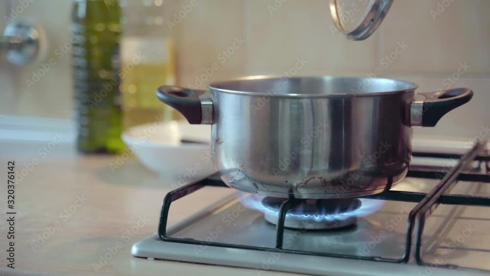 Hand taking off lid from pan, dripping condensation. Dolly right, shallow focus Hand taking off lid from pan, dripping condensation. Dolly right, shallow focus