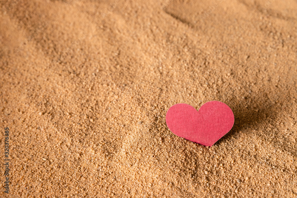 The burgundy heart is stuck in the sandy surface. The burgundy heart is stuck in the sandy surface.