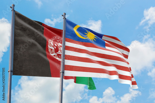 Malaysia and Afghanistan flags waving in the wind against white cloudy blue sky together. Diplomacy concept  international relations.