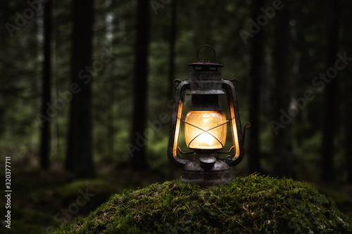  Old kerosene lamp on the moss in mysterious dark forest. Vintage lantern lighting. Copy space.
