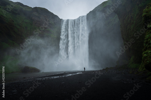 Majestic skogafoss in Iceland, cloudy day with one person in front