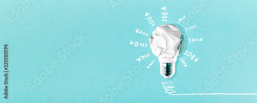 crumpled white paper lightbulb with inscription idea on blue background, panoramic mock-up with space for text photo