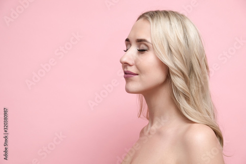 Beautiful blond woman with naked shoulders on pastel pink background. Beauty, cosmetics and skin care concept