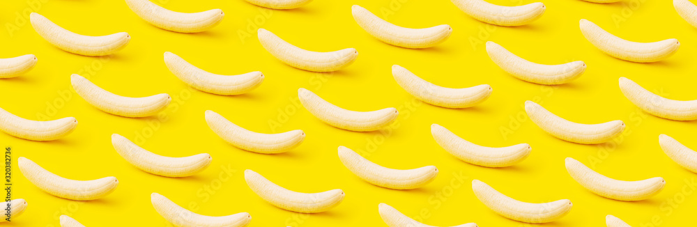 Ripe peeled bananas on yellow background, minimal diet concept, panoramic pattern