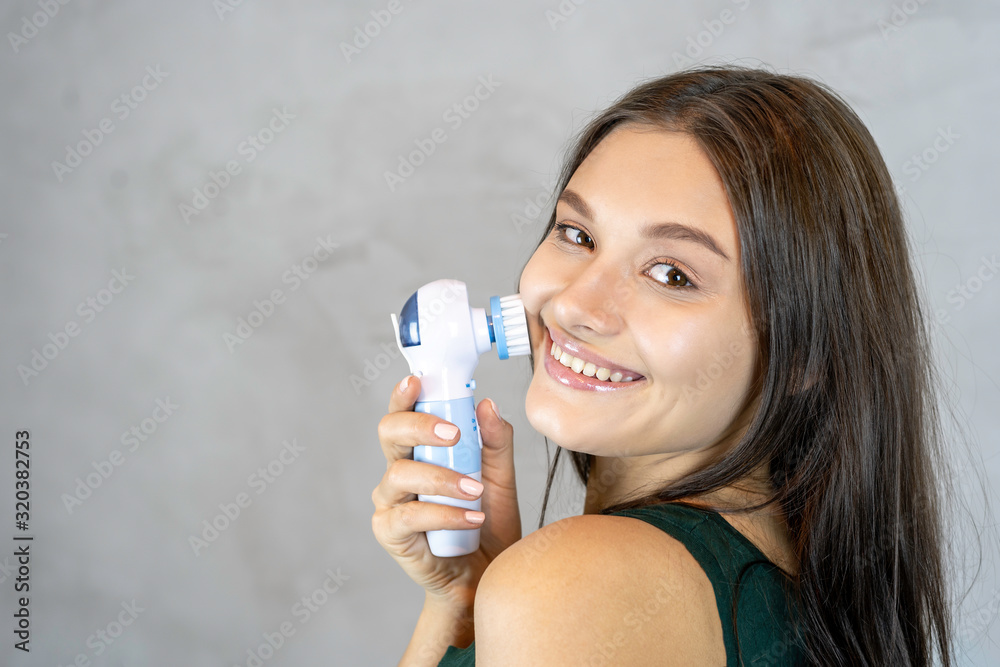 Young pretty woman doing skin care procedure. Cleaning face with machine copy space Young pretty woman doing skin care procedure. Cleaning face with machine copy space