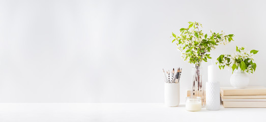 Home interior with decor elements. Spring flowers in a vase, office supplies on a light background