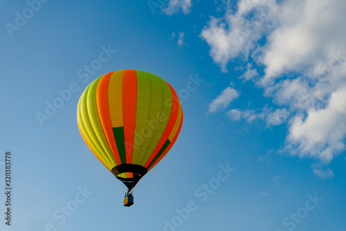 Colorful hot air balloons flying in blue sky. Few colorful, hot air balloons descending at the Balloon Festival. © Dmitrii