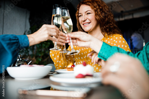 Cheerful woman clinking glasses of champagne with friends