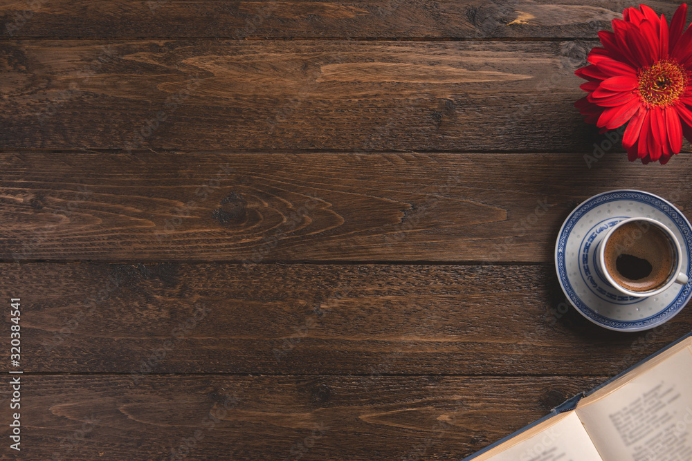 Fototapeta premium Open book, cup of coffee, flower, on wooden background. Flat lay, top view, copy space.
