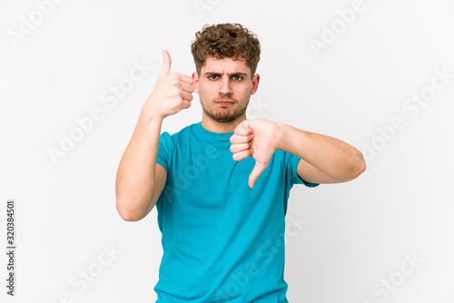 Young blond curly hair caucasian man isolated showing thumbs up and thumbs down, difficult choose concept