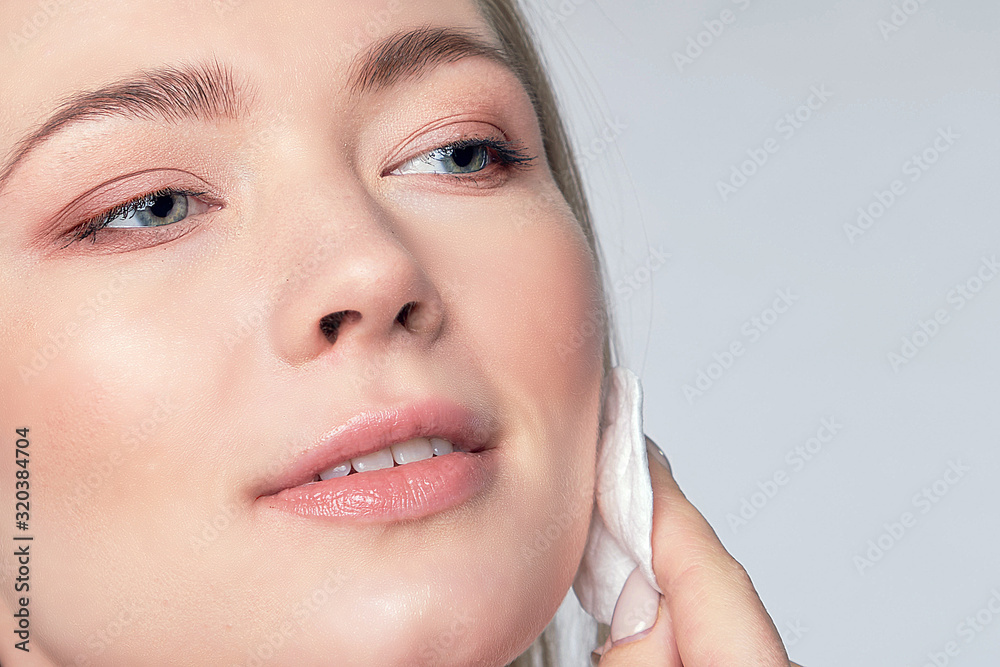 Healthy fresh girl removing makeup from her face with cotton pad. woman with a sponge wihte background cotton pad problem skin