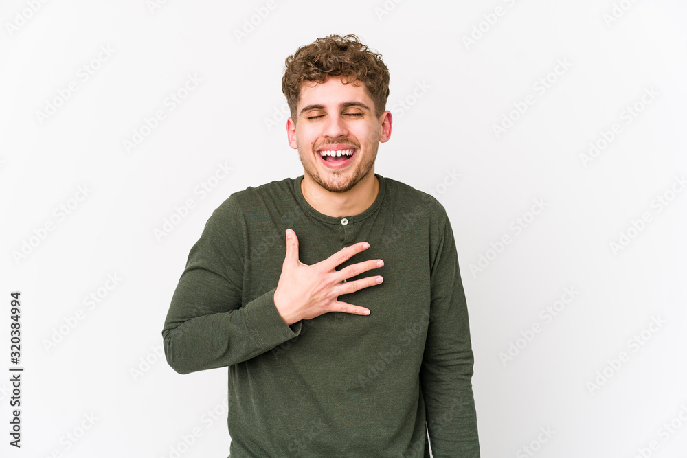 Young blond curly hair caucasian man isolated laughs out loudly keeping hand on chest. Young blond curly hair caucasian man isolated laughs out loudly keeping hand on chest.