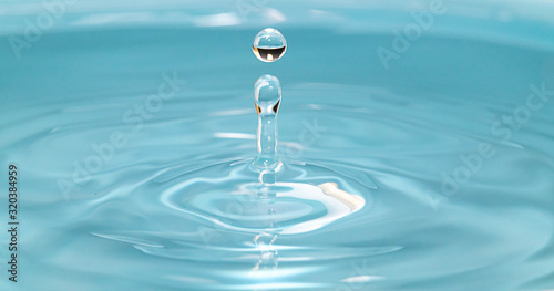 Closeup Water drop falling on the surface of the water and beautiful circular wave ripple, fresh natural mineral water drink water concept