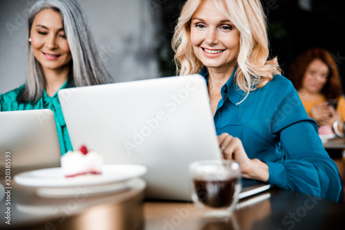 Cheerful women using modern notebooks in cafe