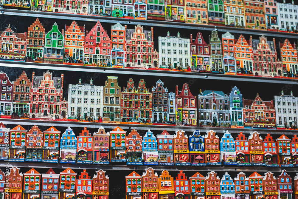 Traditional souvenirs from Amsterdam - fridge magnets, rows of Delftware porcelain, Dutch style houses, dutch wooden clogs, wooden tulips and windmill miniature, shop window store front, Netherlands