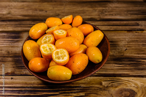 Plate with kumquat fruits on wooden table