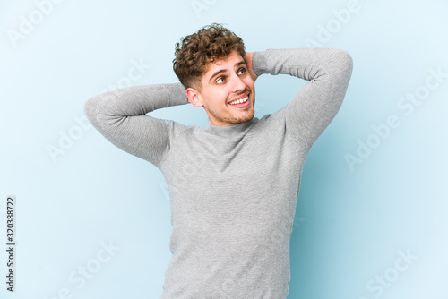 Young blond curly hair caucasian man isolated stretching arms, relaxed position.