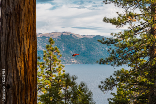A red helicopter flies over Lake Tahoe near Crystal Bay