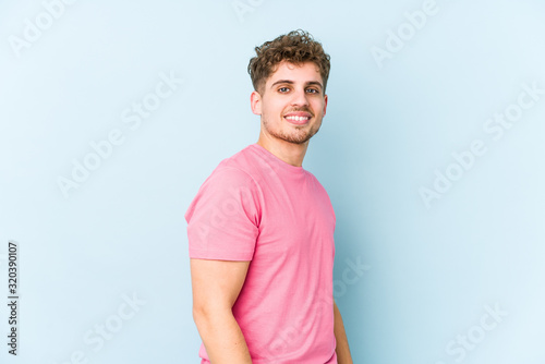 Young blond curly hair caucasian man isolated looks aside smiling, cheerful and pleasant.