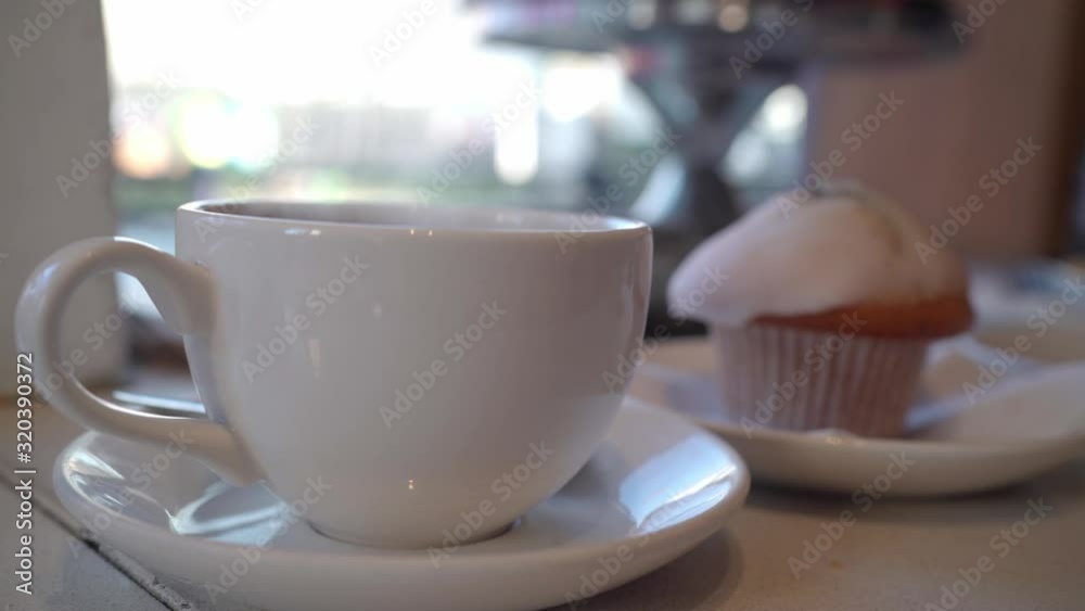 Coffee smoking by the cake near the window in a coffee shop at daytime Coffee smoking by the cake near the window in a coffee shop at daytime
