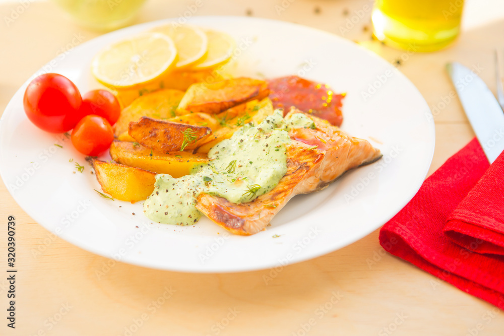 Fried salmon and vegetables on plate on wooden table