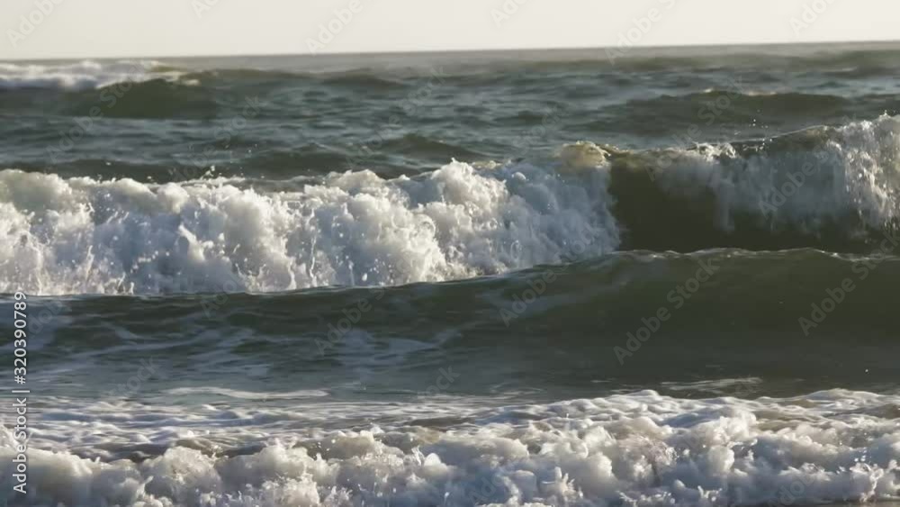 Waves come in on beach during sunset in Bali.