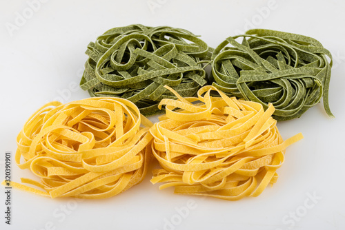 Uncooked tagliatelle pasta, green and yellow, four nests