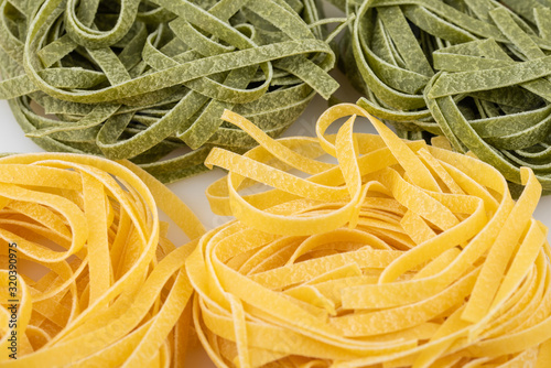Uncooked tagliatelle pasta, green and yellow, four nests