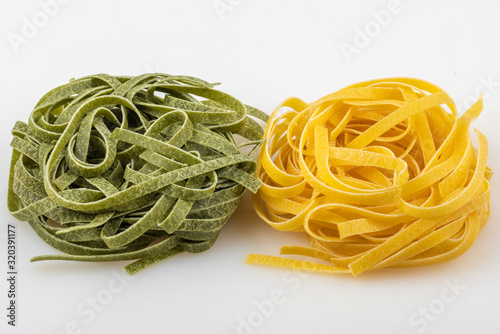 Uncooked tagliatelle pasta, green and yellow, two nests