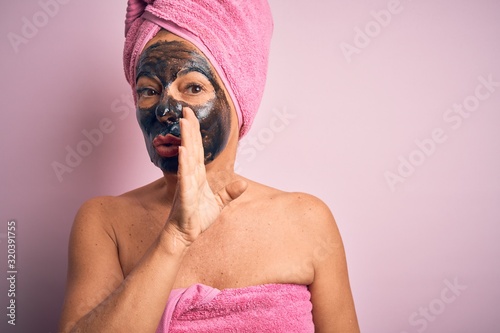 Obraz na płótnie Middle age brunette woman wearing beauty black face mask over isolated pink back