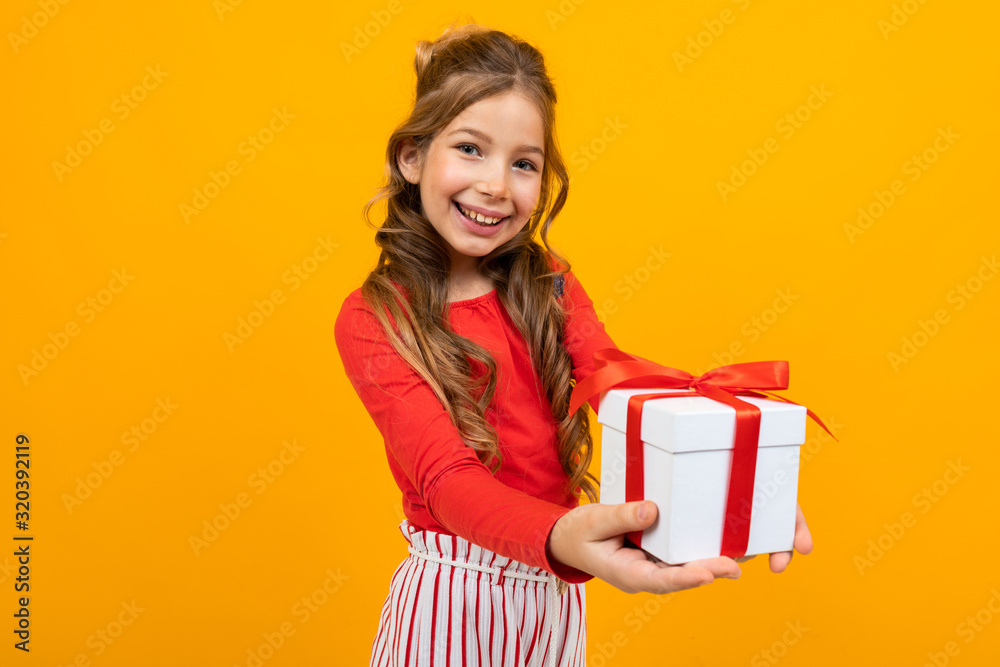 beautiful girl holds out a box with a birthday present on a yellow background beautiful girl holds out a box with a birthday present on a yellow background