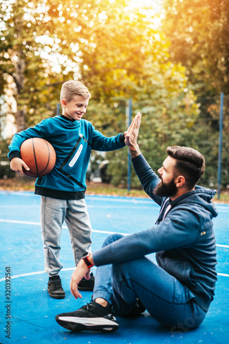 Fototapeta Naklejka Na Ścianę i Meble -  Father and his son enjoying together on basketball court.