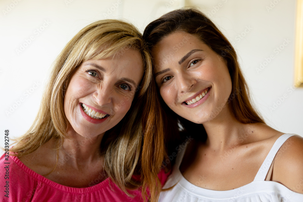 Mother and daughter smiling to camera at home