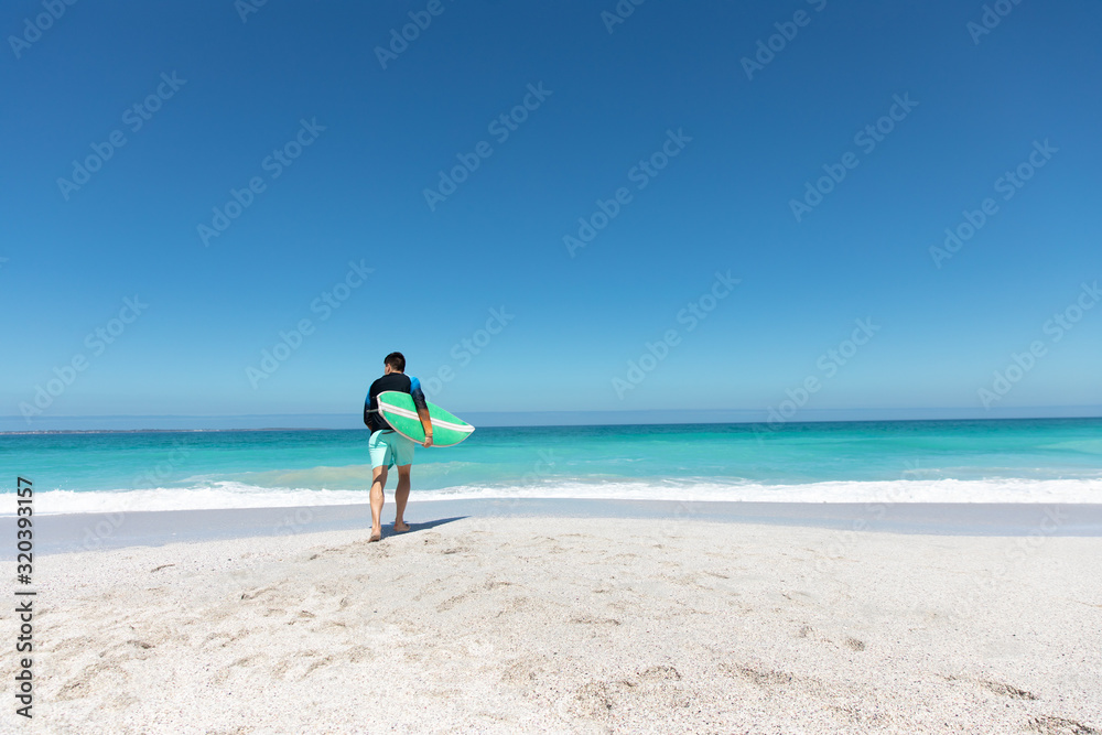 Young man walking with surfboard at the beach