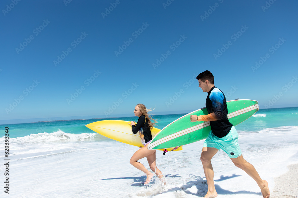 Young couple running with surfboard